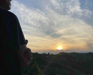 Ein Mensch blickt in den Sonnenuntergang über den Hügeln
