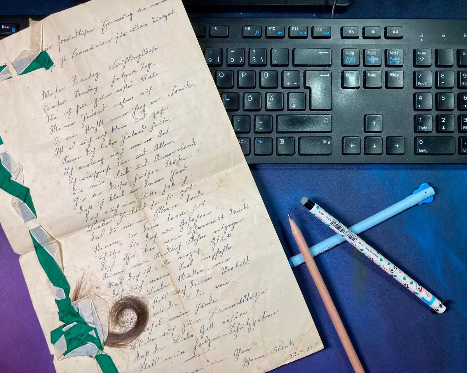 Brief in alter Schrift mit Tastatur und bunten Gelschreibern
